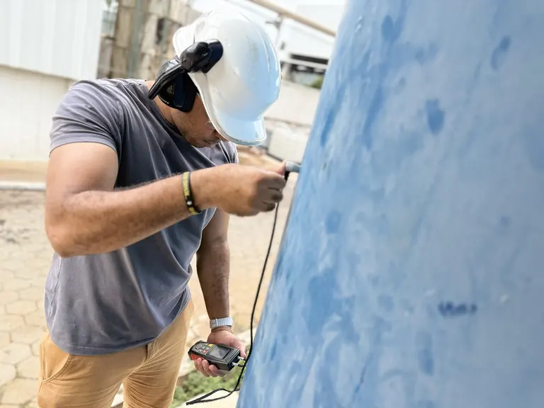 Profissional realizando medição na parede externa de um vaso de pressão