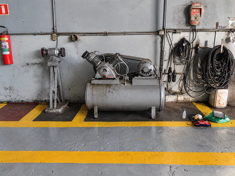 Compressor e reservatório de ar comprimido em ambiente industrial