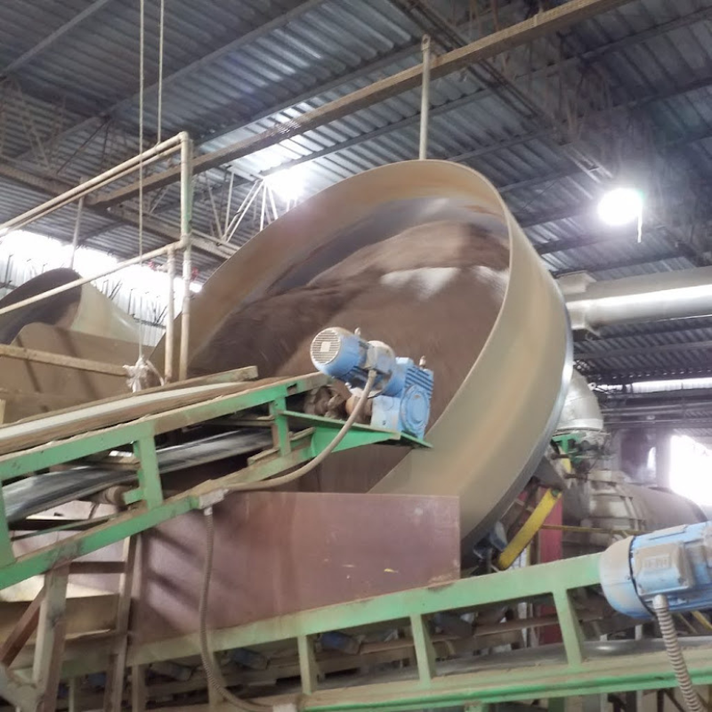 Vista de esteira transportadora em operação, movendo materiais granulados em ambiente industrial, necessitando de inspeção e manutenção conforme normas NR12.