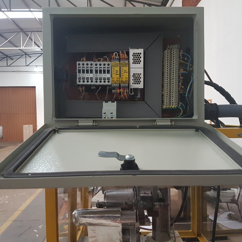 Vista detalhada de caixa de controle elétrico industrial, com componentes eletrônicos visíveis, necessitando de inspeção e manutenção conforme normas NR12.