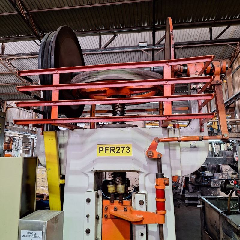 Vista detalhada de máquina industrial de processamento com componentes mecânicos e elétricos visíveis, necessitando de inspeção e manutenção conforme normas NR12.