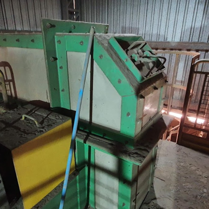 Vista de máquina industrial complexa com componentes metálicos pintados em verde e amarelo, necessitando de inspeção e manutenção conforme normas NR12.