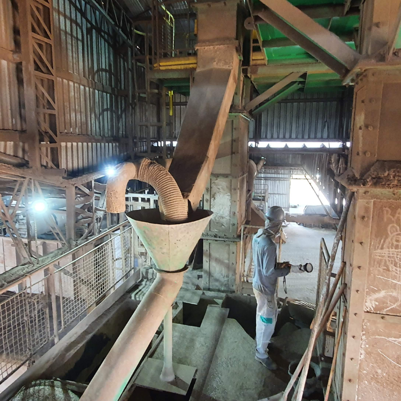 Trabalhador realizando inspeção em sistema de tubulações e funis industriais, necessitando de conformidade e segurança conforme normas NR12.