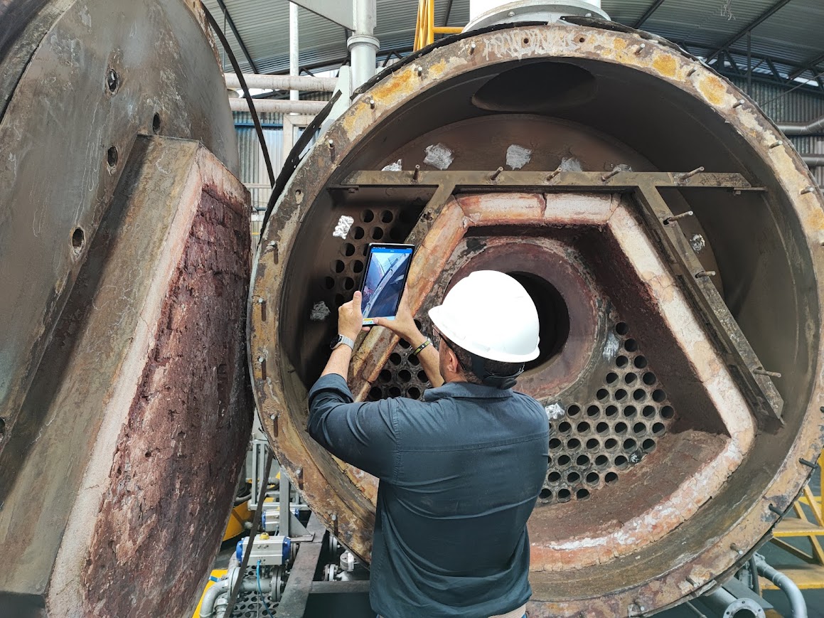 Engenheiro realizando inspeção em caldeira industrial aberta, avaliando integridade estrutural e conformidade com a NR13.