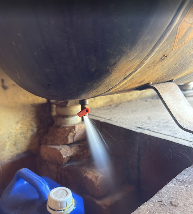 Vaso de pressão sendo drenado por válvula inferior, liberando água acumulada e prevenindo corrosão interna conforme a NR-13.