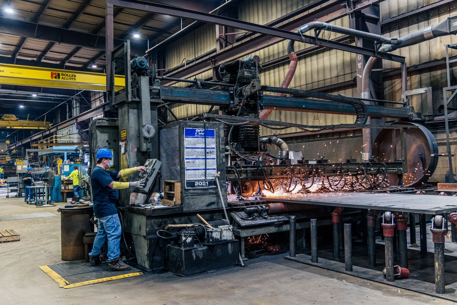 Trabalhador opera máquina industrial em área de produção