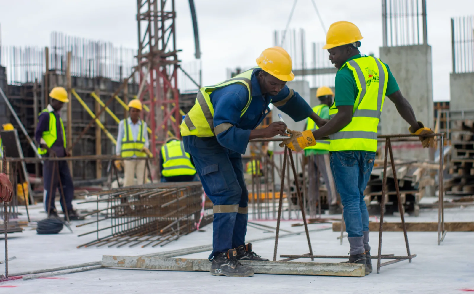 Equipe trabalha em canteiro de obras usando capacetes e coletes