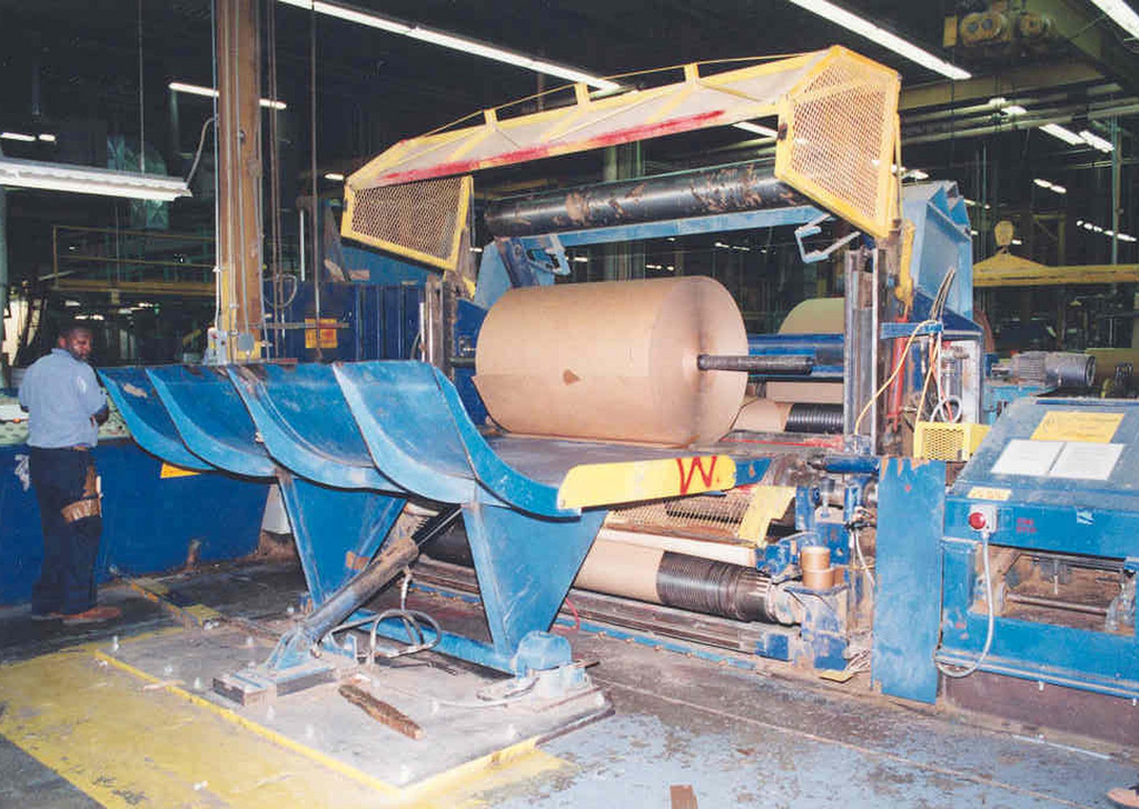 Máquina industrial de processamento e corte de papel ilustrando proteção de zonas perigosas conforme NR-12