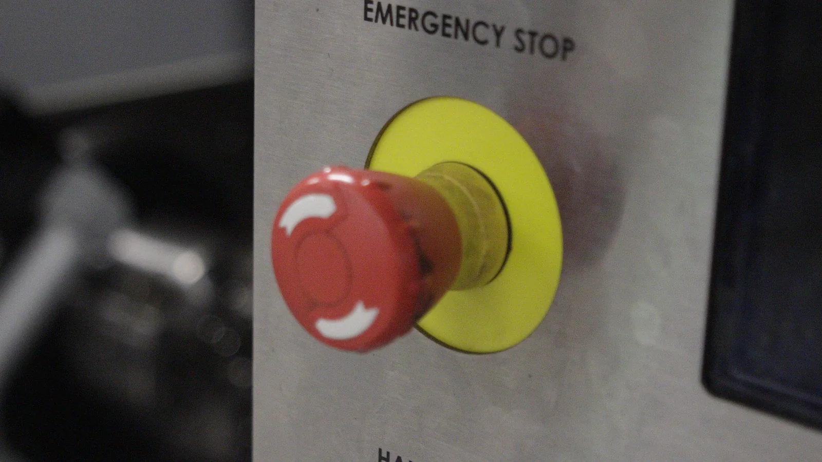 Botão de emergência vermelho e amarelo no painel de uma máquina CNC
