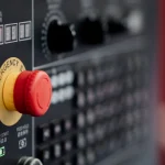 Botão vermelho de parada de emergência em painel de comando de máquina industrial