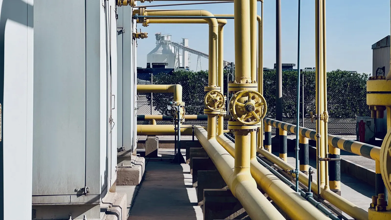 Tubulações industriais amarelas e válvulas conectadas a equipamento de processo