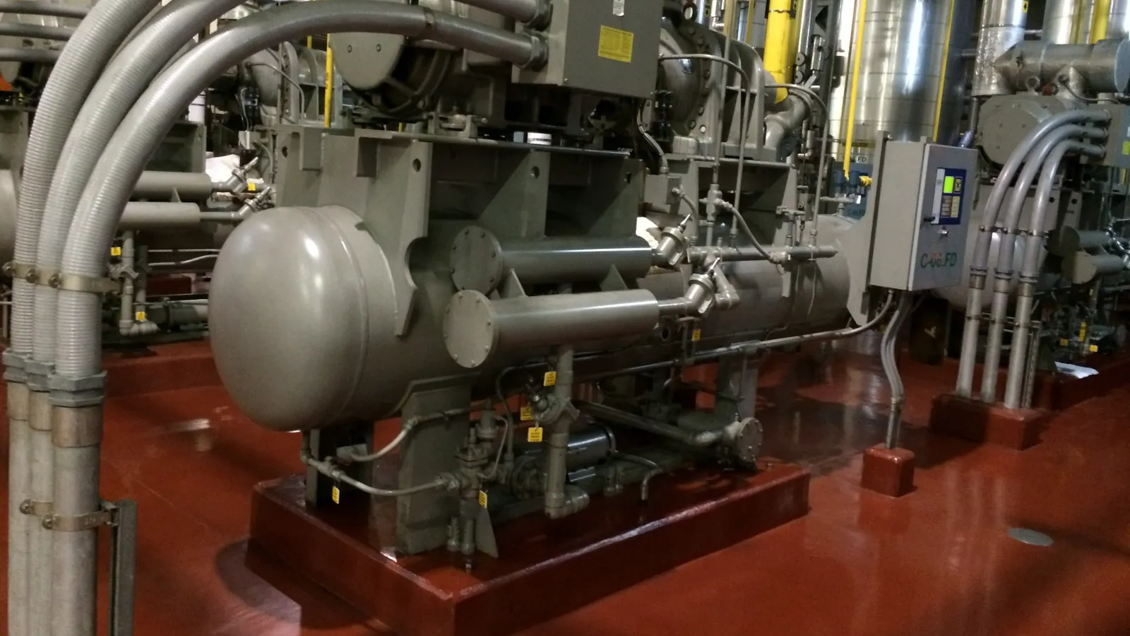 Unidade de compressão industrial com vaso de pressão horizontal em primeiro plano sobre base pintada