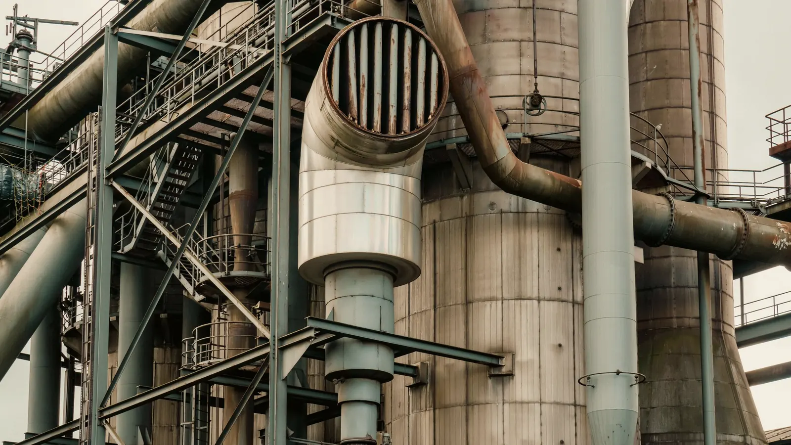 Conjunto de tubulações metálicas em instalação industrial, com diferentes trajetos e conexões