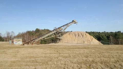 Correia transportadora elevada atravessando área industrial aberta para movimentação de agregados