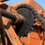 Detalhe de corrente de rolos engrenada em roda dentada de equipamento histórico.