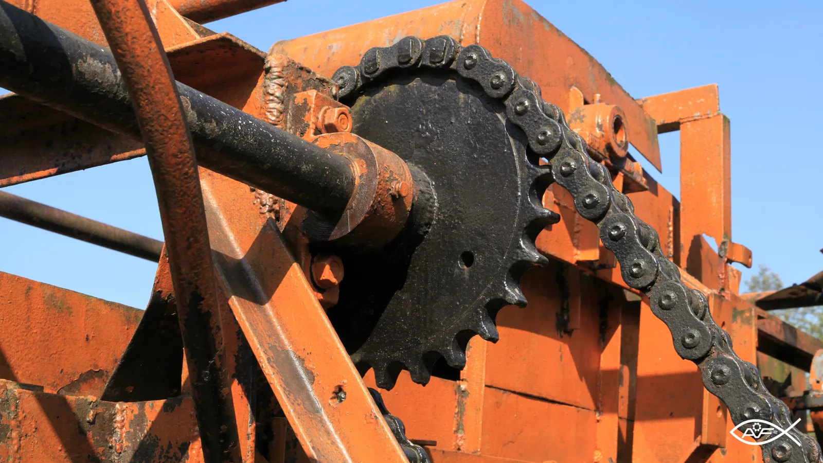 Detalhe de corrente de rolos engrenada em roda dentada de equipamento histórico.