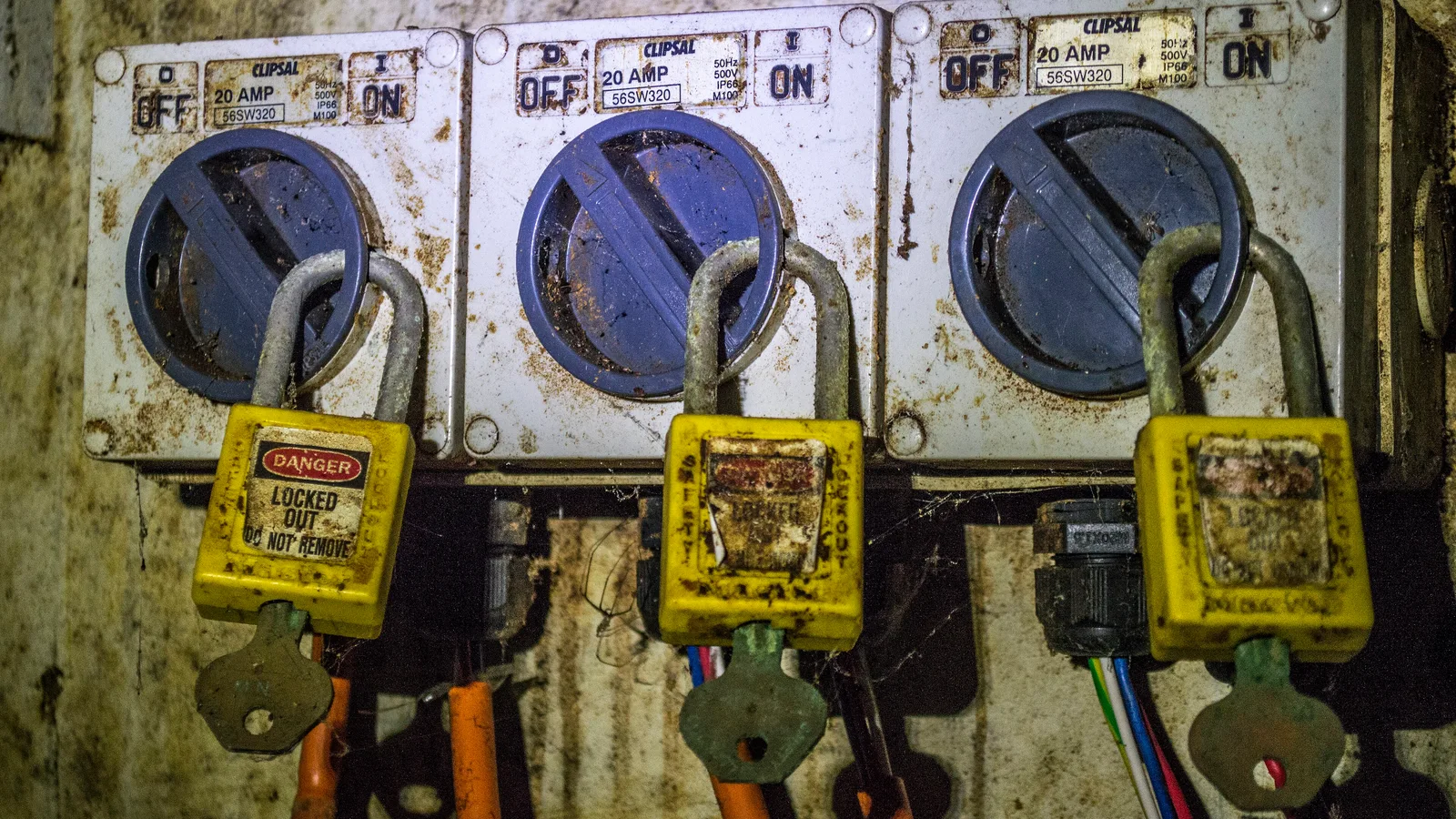 Dispositivos de seccionamento elétrico com cadeados e etiquetas de bloqueio.