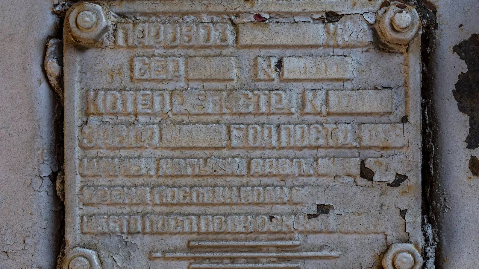 Placa metálica de identificação de caldeira fixada com parafusos, com letras em relevo parcialmente apagadas pela tinta e pela corrosão